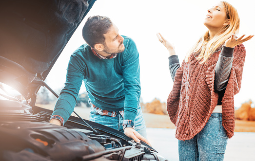 Young couple on a roadtrip having a problem with their car